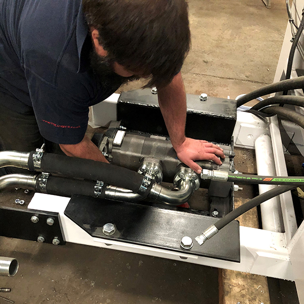 A Volumech employee works on a hydraulic fitting in the workshop.